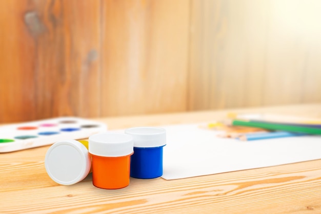Trzy puszki farby i papieru z ołówkami na drewnianym stole