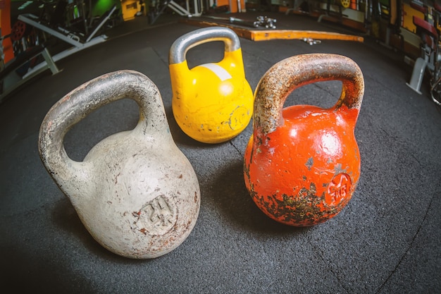 Trzy różne kettlebell na podłodze w siłowni centrum fitness.