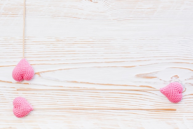 Trzy różowego trykotowego serca na kijach na białym drewnianym tle