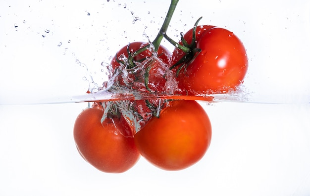 Trzy świeżego Cztery Pomidoru W Pluśnięciu Odizolowywającym Woda