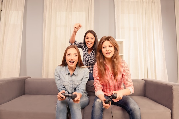 Trzy szczęśliwe atrakcyjne dziewczyny grające w gry wideo w domu