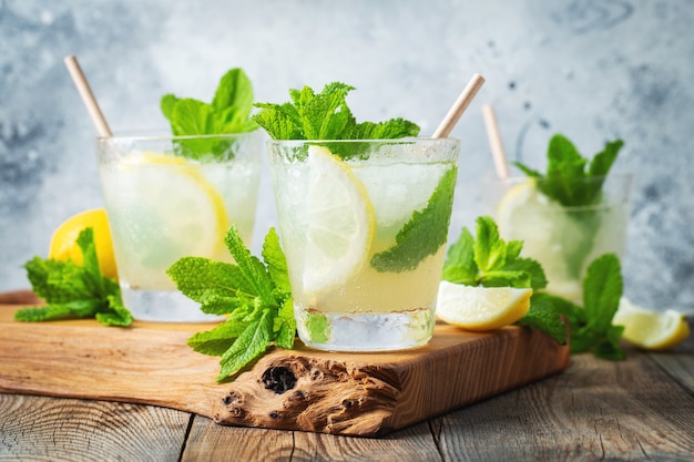 Trzy szklanki koktajlu mojito na drewnianej desce do krojenia