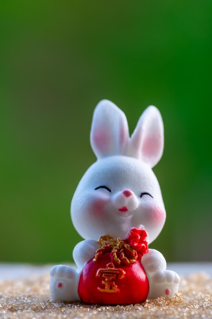 Trzy urocze chińskie króliczki, trzymające czerwoną torbę na pieniądze i uśmiechnięte z zieloną naturą rozmazanym tłem Piękne projekty postaci królików na Święto Środka Jesieni Rok królika 2023 i Wielkanoc