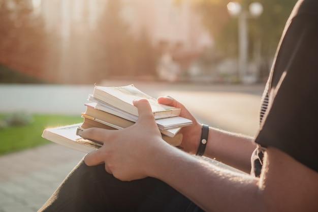 Trzyma stos książek studenckich poza szkołą. Student pierwszego roku czeka na rozpoczęcie zajęć