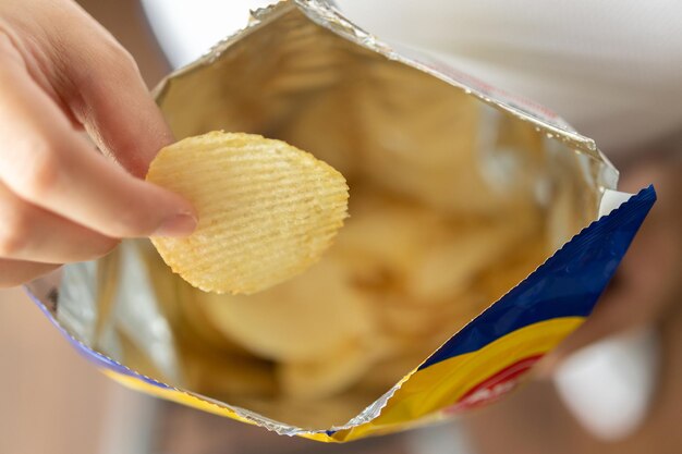 Trzymaj w ręku chipsy ziemniaczane z torbą na przekąski