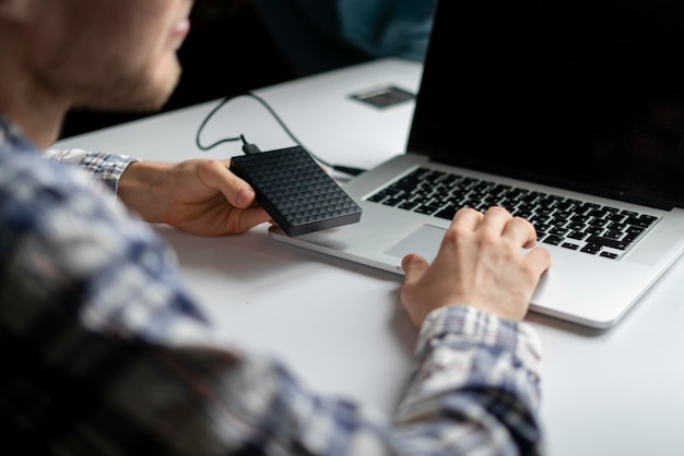 Trzymając kopię zapasową zewnętrznego dysku twardego z archiwum i podłącz go do laptopa