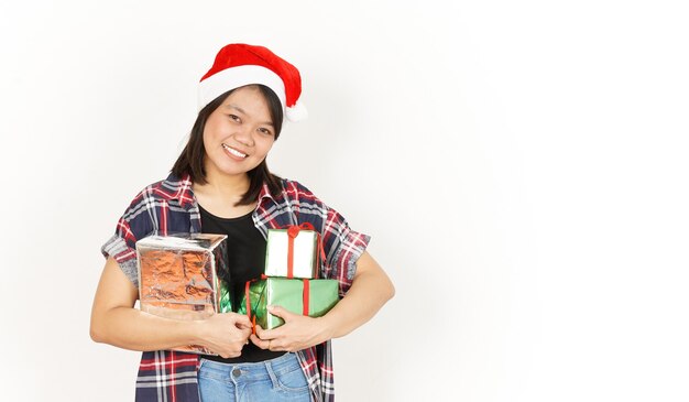 Trzymając prezent świąteczny azjatyckiej kobiety ubrana w czerwoną koszulę w kratę i Santa Hat na białym tle