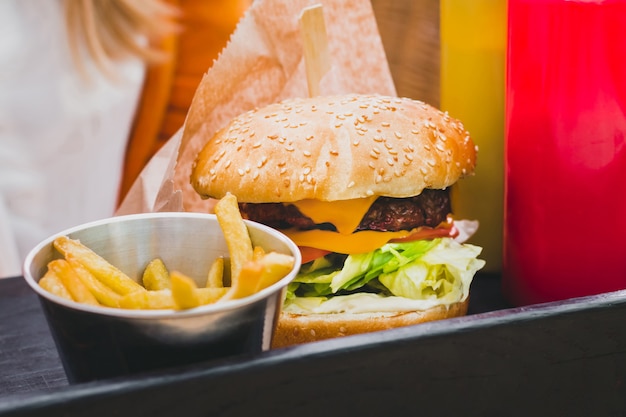 Zdjęcie trzymając się za ręce świeży pyszne burger z frytkami na czarnym drewnianym stole