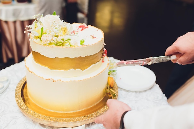 Trzypoziomowy biały tort weselny ozdobiony kwiatami z mastyksu na białym drewnianym stole Obraz do menu lub katalogu wyrobów cukierniczych z miejscem na kopię