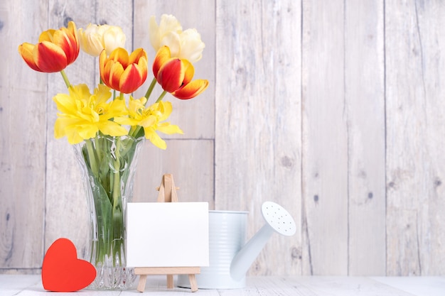 Tulipan kwiat w szklanym wazonie z ramą na zdjęcia na ścianie tle drewniany stół w domu, z bliska, koncepcja projektowa Dzień Matki.