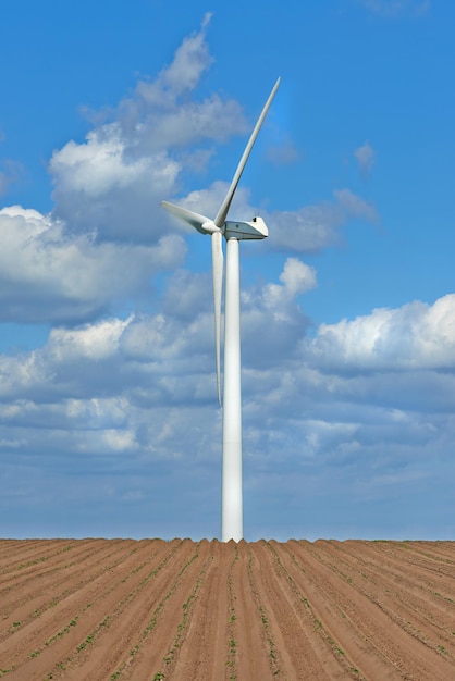 Turbiny wiatrowe Turbiny wiatrowe na farmie z nowo posadzonymi roślinami Pochmurny dzień na gruntach rolnych, gdzie energia wiatru jest głównym zasobem Produkcja zrównoważonej energii elektrycznej i świeżych produktów