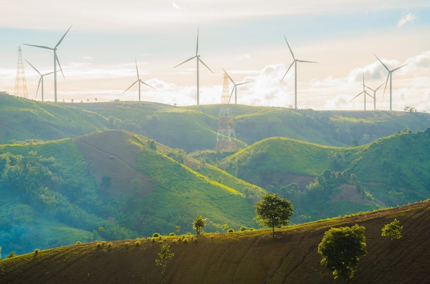 Turbiny wiatrowe wytwarzają energię elektryczną ze światłem słonecznym podczas zachodu słońca w tle