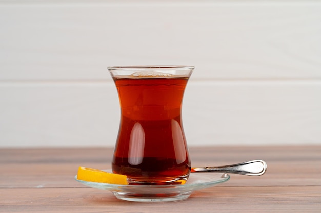 Turecka herbata w szklanym kubku z kawałkiem cytryny na drewnianym stole