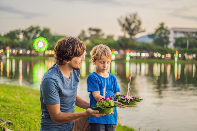 Turyści ojciec i syn trzymają w dłoniach loy krathong i zaraz wyrzucą go do wody