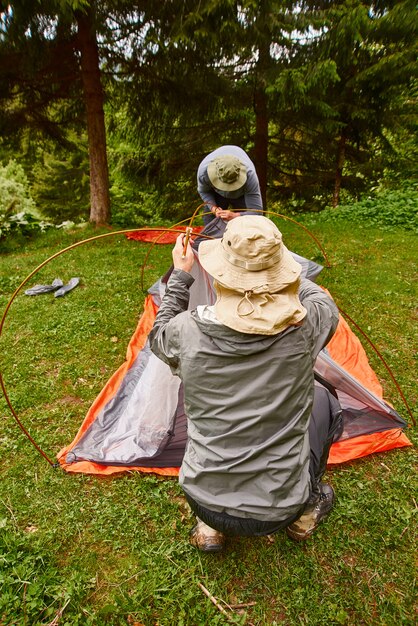 Turyści rozbijający namiot na campingu. Mężczyzna trzyma namiot podczas rozbijania namiotu w lesie