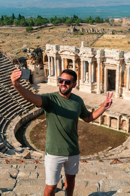 Turysta robi sobie selfie smartfonem ze słynnym teatrem Hierapolis w tle w Pamukkale