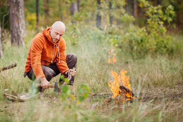 Turysta rozpala ogień w letnim drewnie