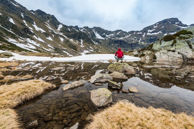 Turysta siedzi na skale w pobliżu jeziora w Andorze