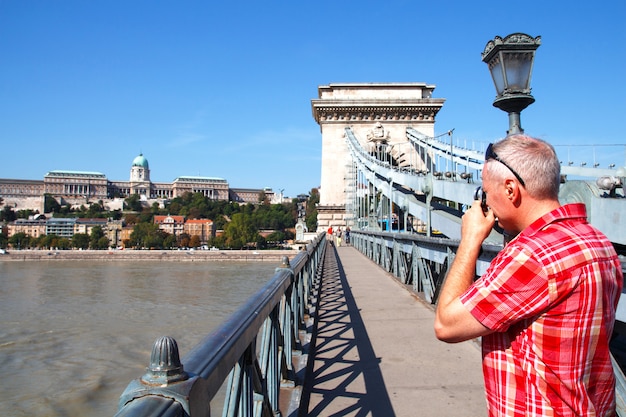 Turysta stojący na deptaku robi zdjęcia budynku parlamentu w Budapeszcie