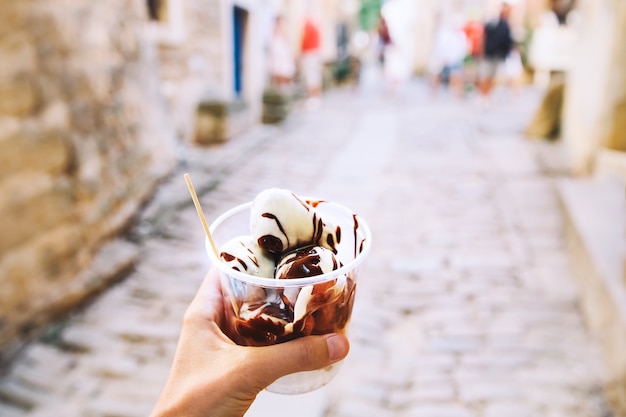 Turysta trzyma w ręku kulki Fritule pączki z czekoladą na tle ulic Chorwacji