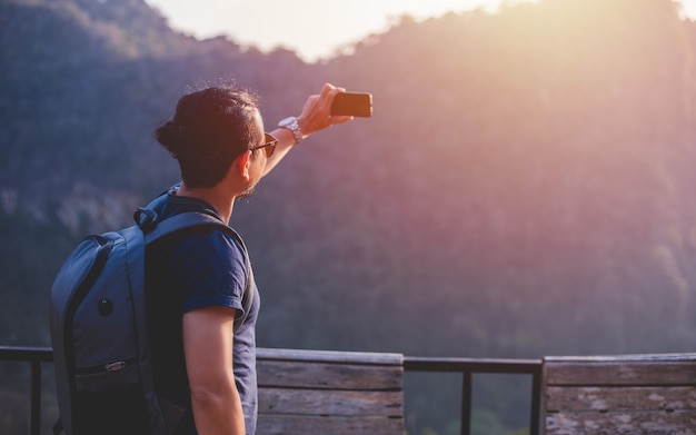 Turysta z Azji korzysta z telefonu komórkowego, aby zrobić selfie w celu udostępniania w mediach społecznościowych za pośrednictwem sieci społecznościowych.