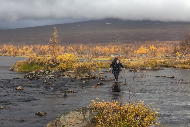 Turysta Z Plecakiem Przemierza Zimny Potok. Na Wycieczce Trekkingowej W Sarek