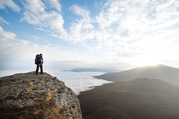 Turysta Z Plecakiem Stojący Na Szczycie Góry Nad Chmurami