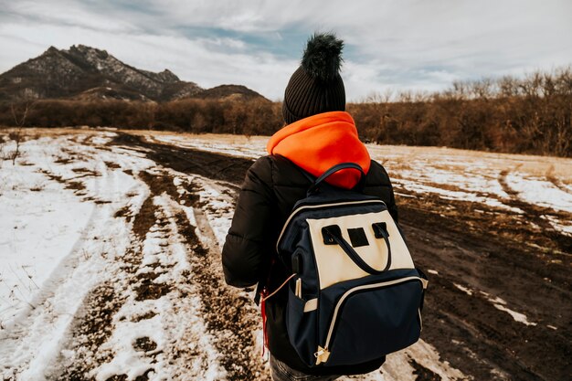 Turysta z plecakiem wspina się po górach. Zdjęcie podróżnika z plecami na tle przyrody.