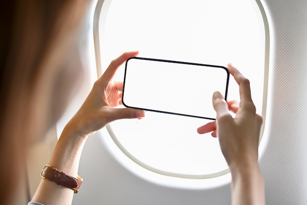 Turystka używająca telefonu komórkowego do robienia zdjęcia nieba poza samolotem w zbliżeniu