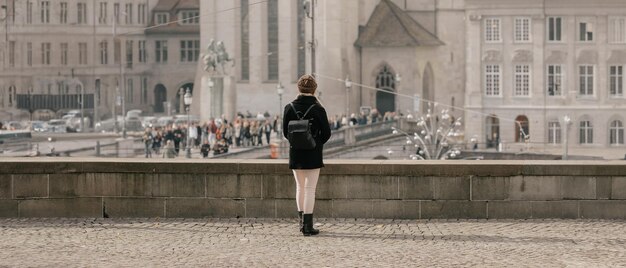 Turystka w ciepłym kapeluszu i płaszczu z plecakiem idąca zimną jesienią w mieście Europy