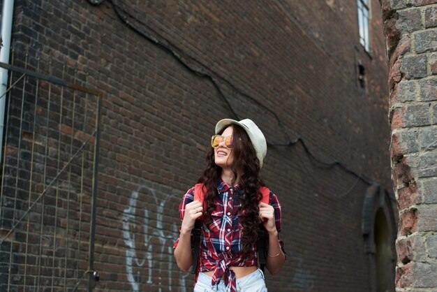 Turystka w kapeluszu i okularach przeciwsłonecznych na tyłach alei z czerwonej cegły