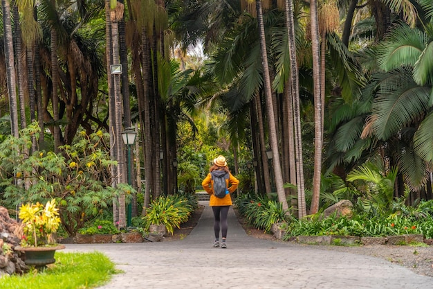 Zdjęcie turystka w słomkowym kapeluszu spacerująca po tropikalnym ogrodzie botanicznym z dużymi palmami