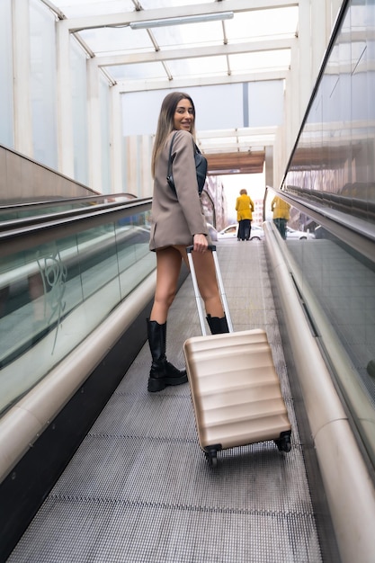 Turystka z walizką w mieście na ruchomych schodach wychodzących z koncepcji wakacji w metrze