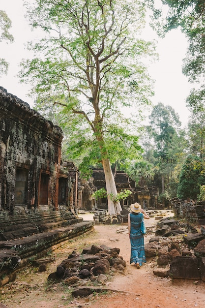 Zdjęcie turystyczna dziewczyna chodzi wśród starożytnych świątynnych budynków w angkor, kambodża.