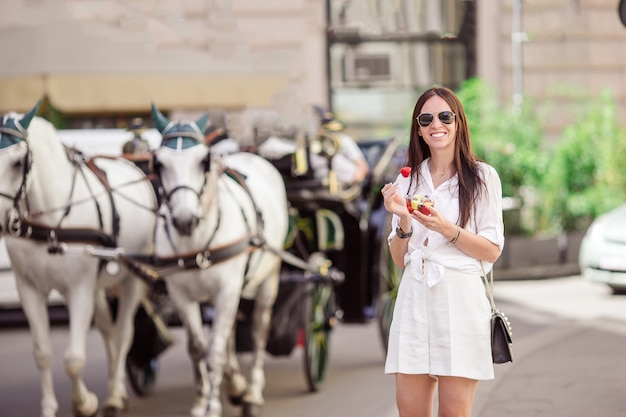 Zdjęcie turystyczna dziewczyna cieszy się wakacje w wiedeń i patrzeje piękne konie w powozie