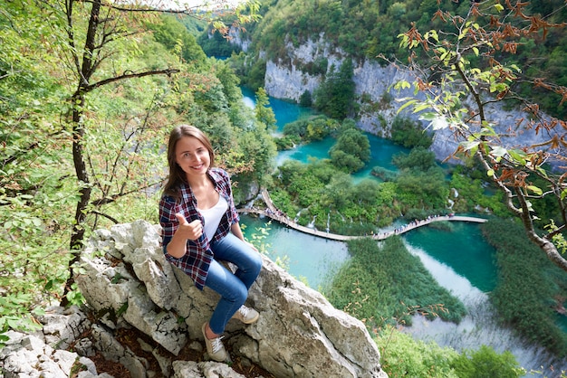 Turystyczna kobieta pokazuje aprobaty przy Plitvice jeziorami