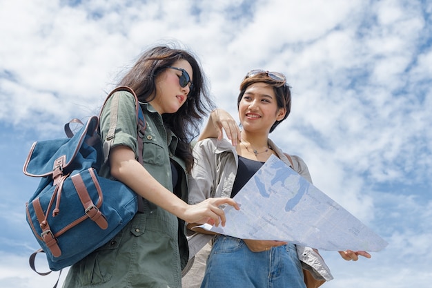 Turystyczna para używa mapę dla znalezienia lokaci pod niebieskim niebem