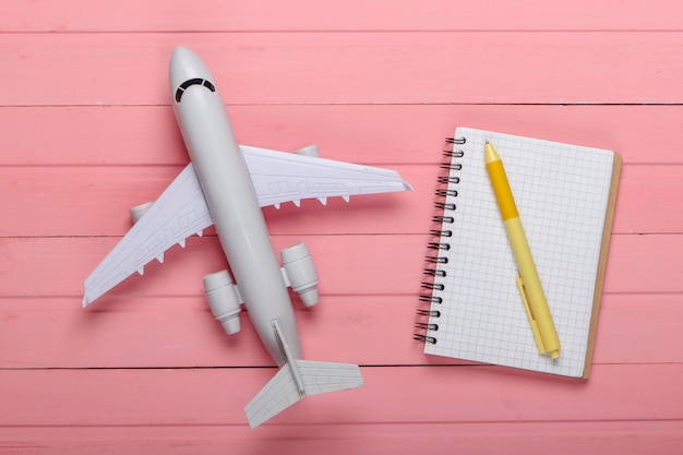 Turystyka lotnicza lub planowanie podróży, układanie na płasko. Figurka samolotu na różowym drewnianym