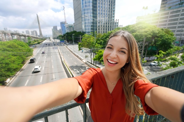 Turystyka w Sao Paulo Piękna uśmiechnięta dziewczyna robi autoportret z mostem Ponte Estaiada w metropolii Sao Paulo w Brazylii