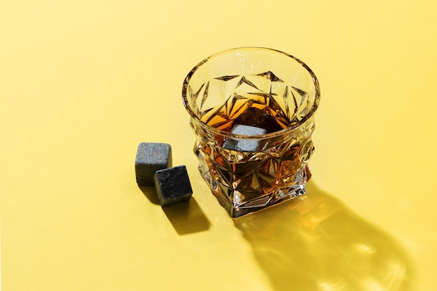 Twarde mocne napoje alkoholowe w szklanej koniakowej tequili szkockiej brandy lub whisky na żółtym tle z twardymi światłami i cieniami widok z góry