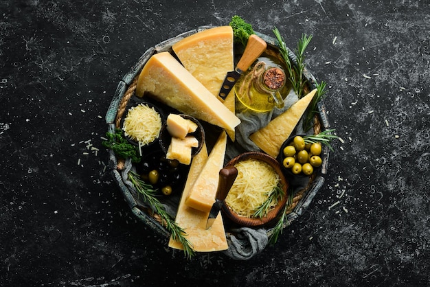 Twardy ser z oliwkami i nożem do sera na czarnym tle kamienia Parmezan Widok z góry Wolne miejsce na tekst