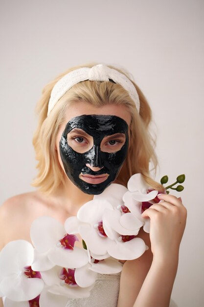 Twarz kobiety z czarną maską peelingującą na skórzenakładanie maski kosmetycznej na twarz
