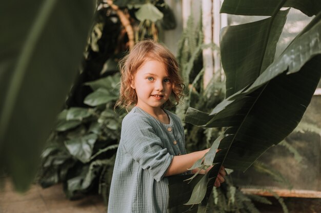 twarz małej dziewczynki otoczonej tropikalnymi liśćmi Naturalne kosmetyki koncepcja urody
