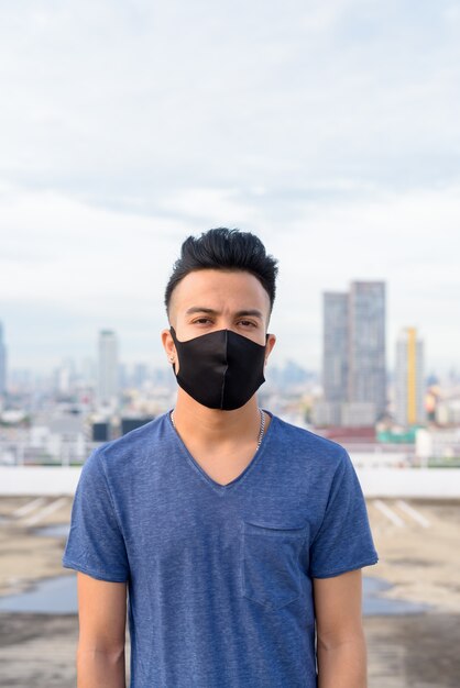 Twarz młodego wielo- etnicznego mężczyzna jest ubranym maskę przeciw widokowi miasto