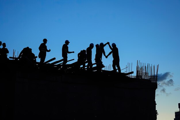 Zdjęcie two construction workers shake hands on top of a building under the sky