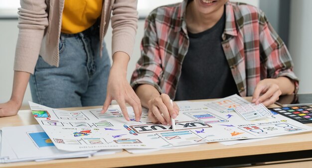 Twórca UX i projektant UI brainstormują o projektowaniu interfejsu aplikacji mobilnej z kodem kolorowym klienta w biurze