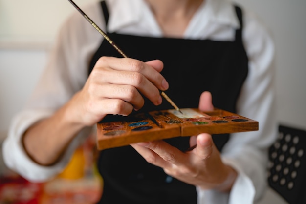 Twórczy artysta pracujący nad sztuką kolorów do rysowania obrazu za pomocą pędzla w hobby, warsztaty rzemieślnicze z pędzlem akwarelowym z płótnem w studio, sztalugą paletową i tłem do projektowania grafiki