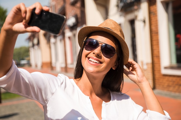 Zdjęcie tylko ja i mój nowy kapelusz! piękna młoda funky kobieta dopasowująca kapelusz i robiąca selfie stojąc na zewnątrz