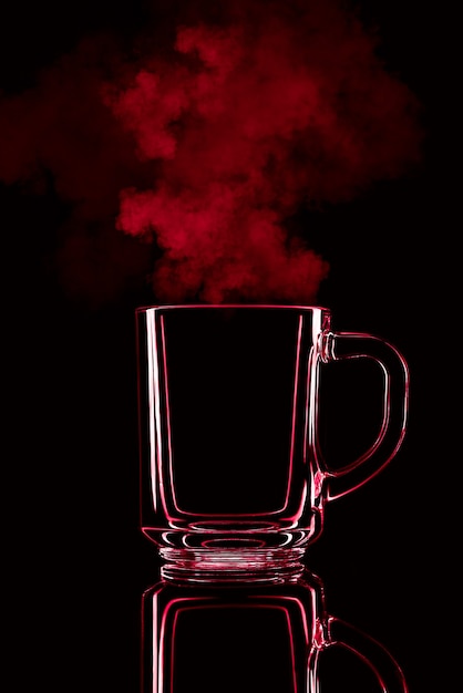 Tylko szklanka na czarnym tle z odbiciem. Kolor czerwony, z parą. Odosobniony.