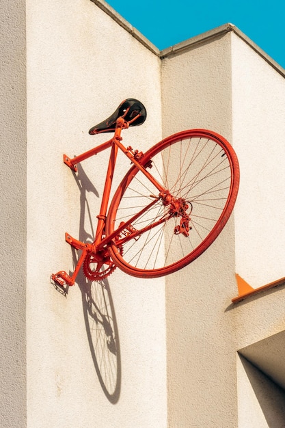 Tylna połowa czerwonego zabytkowego roweru przypięta do ściany, rzucająca cień koła